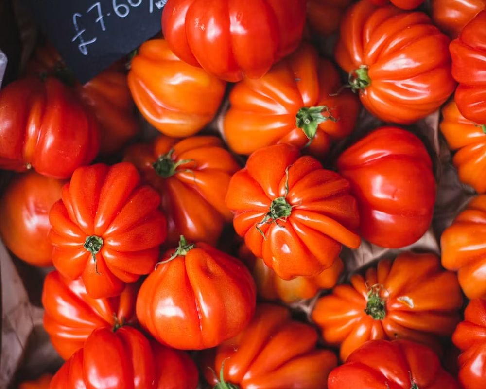 Market crates of tomatoes with a handwritten chalkboard price sign