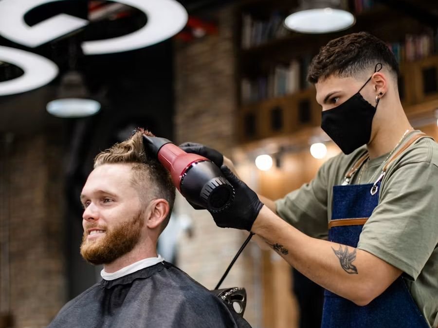 Barber giving a client a fresh cut in a busy barbershop