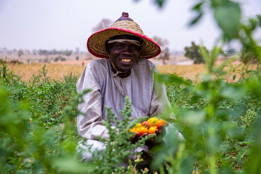 Our produce partner smiling, holding a crate of fresh greens